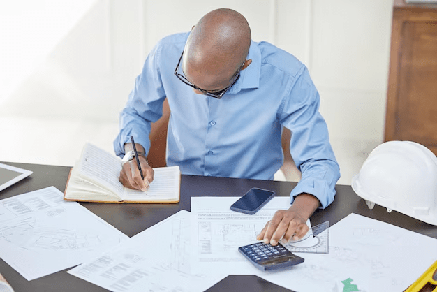 A man writing down his debt with a calculator on the table to manage Credit Card Balances